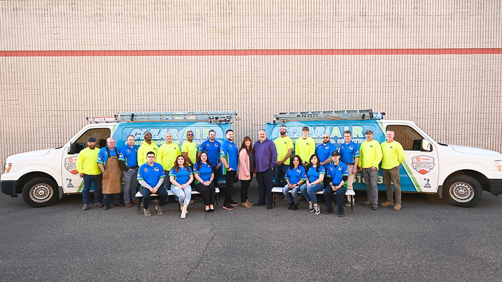 The Clear Air Conditioning & Heating team outside with service trucks.