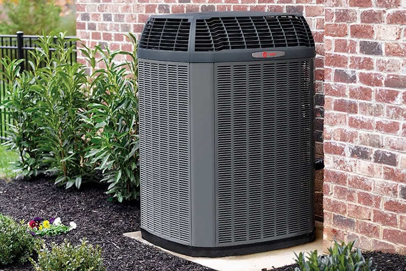 Spring AC Maintenance Tips. Photo of an HVAC installed outside of a brick home.